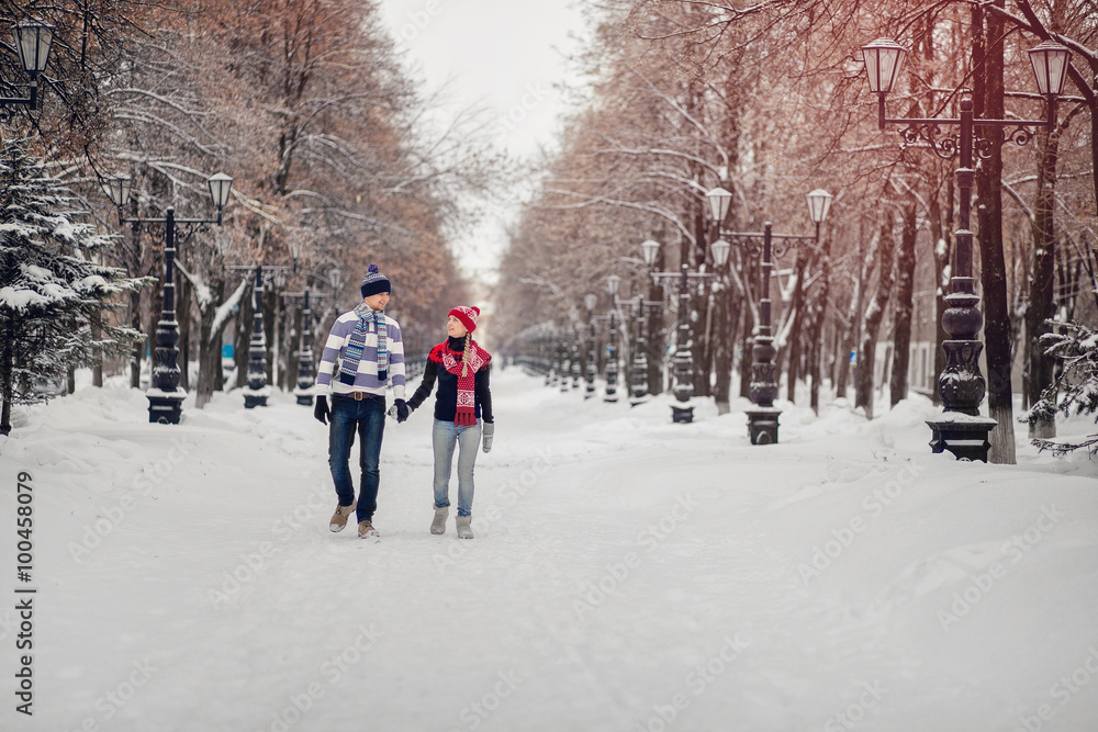 A couple in love cute sweaters for walks in the snowy winter Park. The concept of Valentine's day