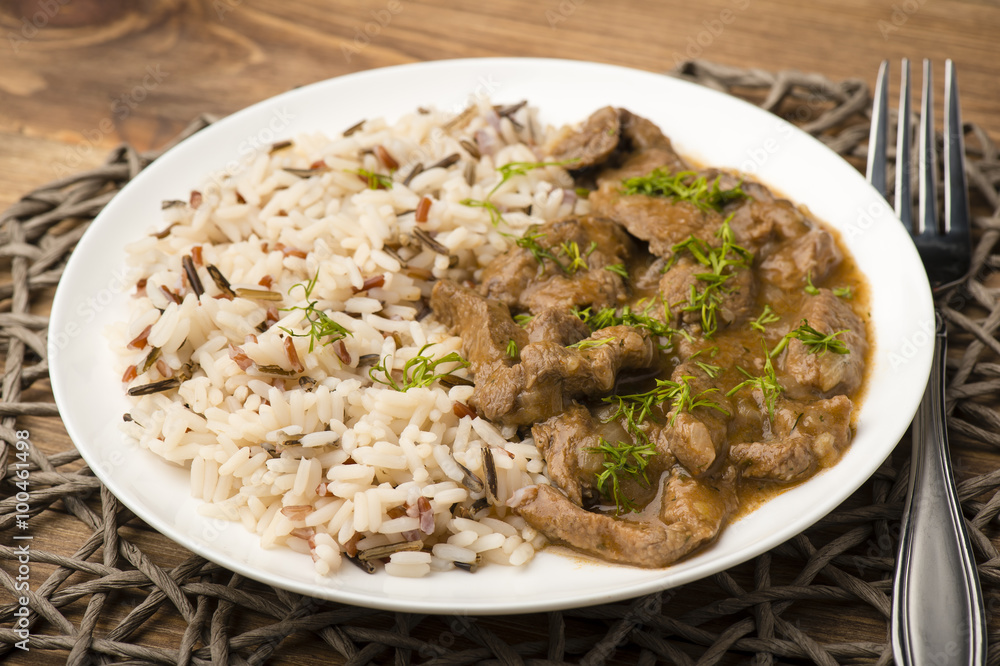 Stewed beef and rice on the white plate on wooden background. Stewed beef and rice on the white plate on wooden background.