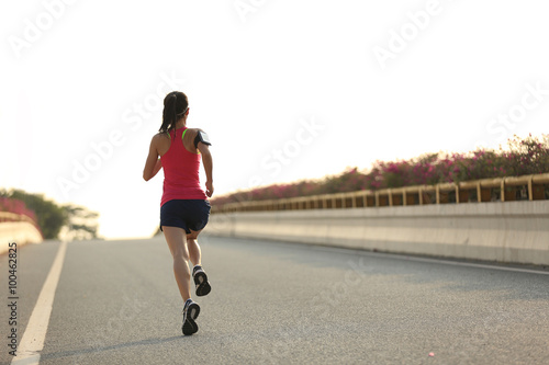 young woman runner running on city bridge road © lzf