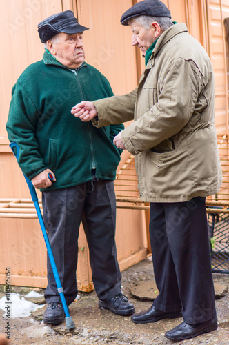 Two aged men discuss in the street