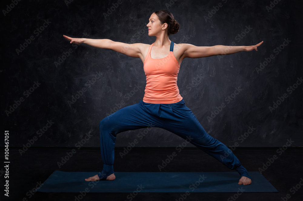 Woman practices yoga asana utthita Virabhadrasana Woman practices yoga asana utthita Virabhadrasana