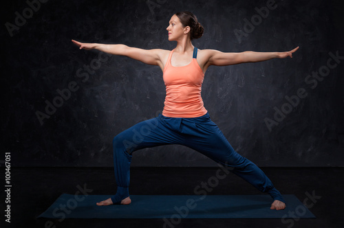Woman practices yoga asana utthita Virabhadrasana