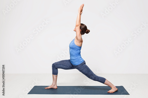 Woman practices yoga asana utthita Virabhadrasana
