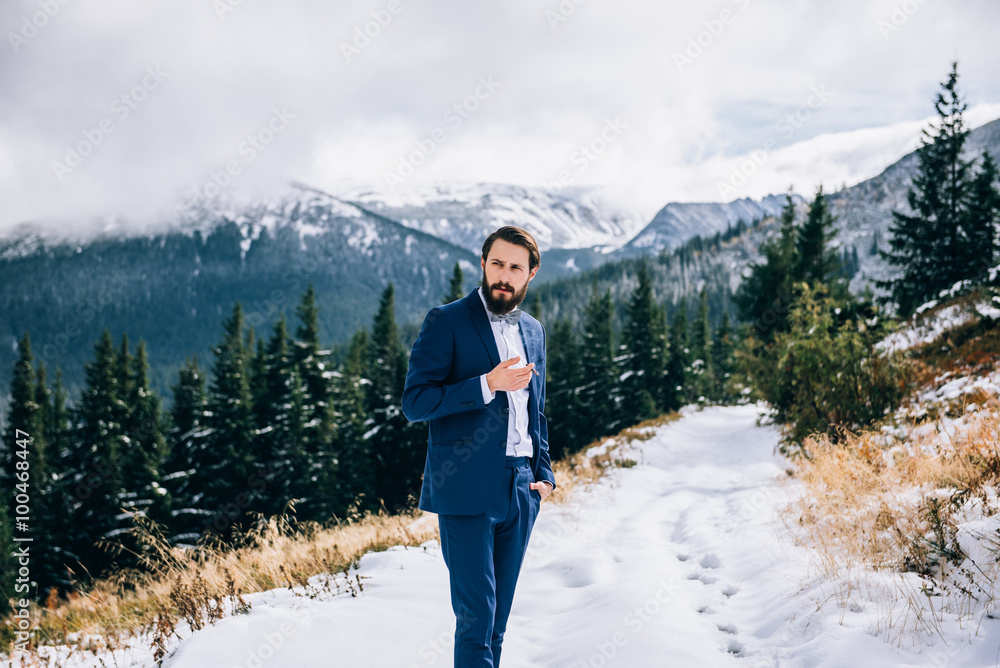 groom in a blue suit in the mountains Carpathians