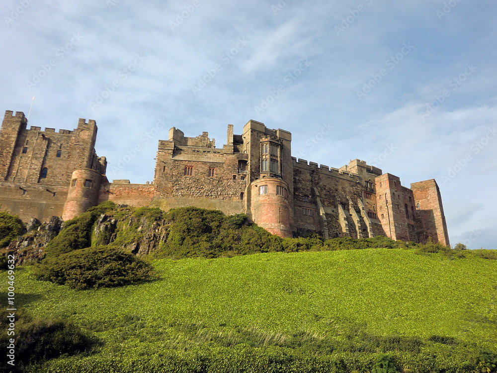 Bamburgh castle in eastern England with blue sky and green grass