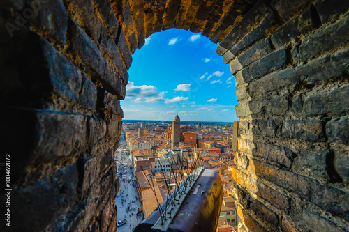 Views from Garisenda tower in Bologna, Italy throug a window to he city center with a surveillance camera in the foreground and the bricks of the tower as the natural frame photo