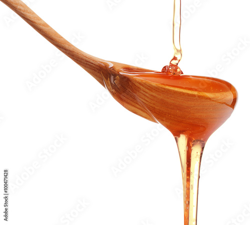 Honey dripping from a wooden honey dipper isolated on white back