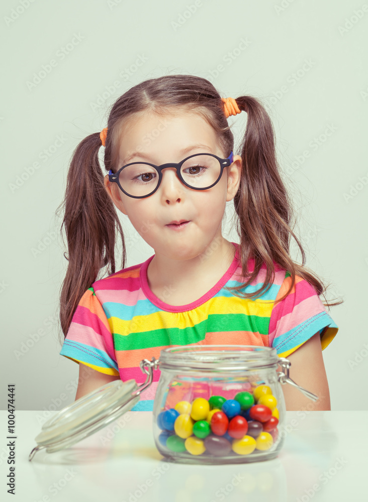 beautiful cute little girl eating candy from candy jar Stock Photo