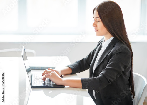 Portrait of young pretty business woman with laptop in the offic