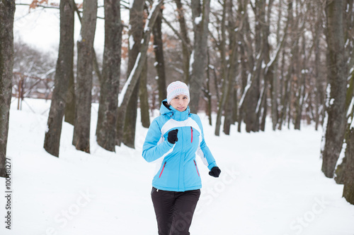 Young slim woman jogging in winter park