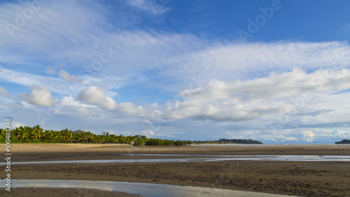 Cloudscape on a blue sky on a plain sand beach