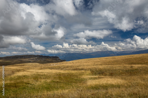 Autumn blue sky with white clouds and mountains on the yellowed