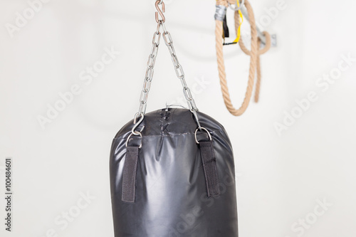 Punching bag suspended from the ceiling with a rope in the backg © edojob