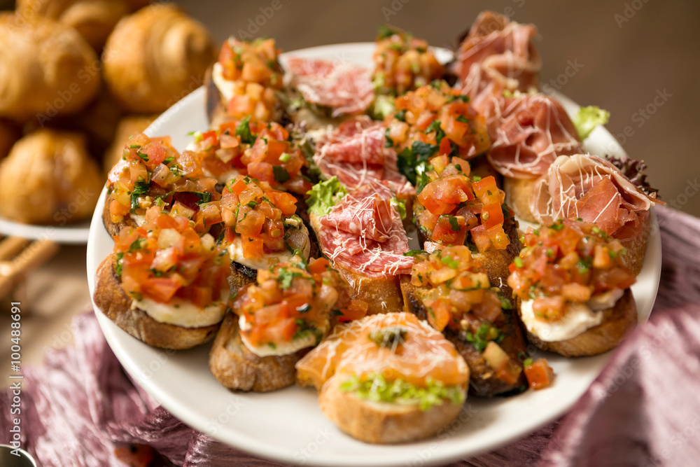 a plate of bruschetta with mozzarella, prosciutto and vegetables a plate of bruschetta with mozzarella, prosciutto and vegetables