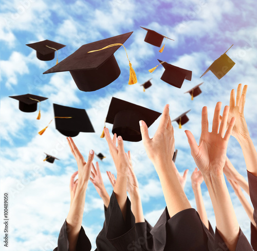 Graduates hands throwing graduation hats in the sky