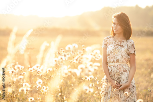 Beautiful young brunette in sunset on a field