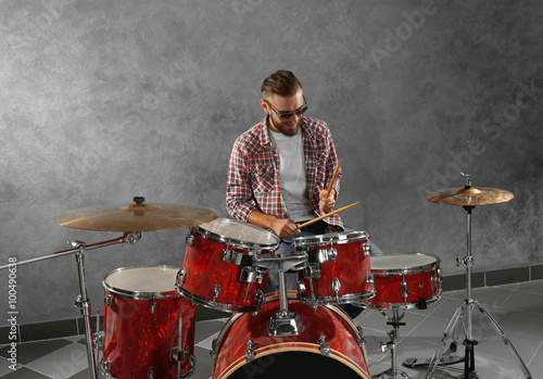 Musician playing the drums on grey wall background