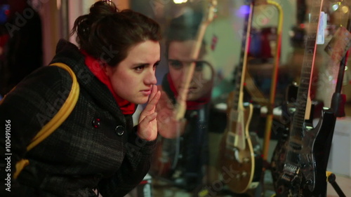 woman looks guitar shop window