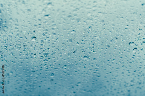 Droplets of rain on a window against a blue sky backdrop