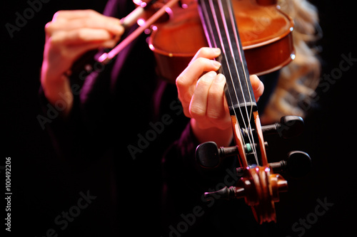 Woman plays violin on black background, close up