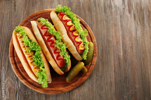 Tasty hot-dogs with vegetables on wooden table