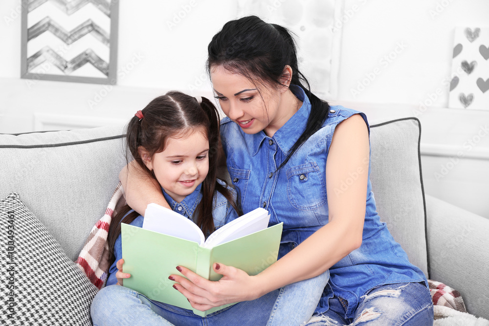 Mother and daughter reading book on the sofa Mother and daughter reading book on the sofa