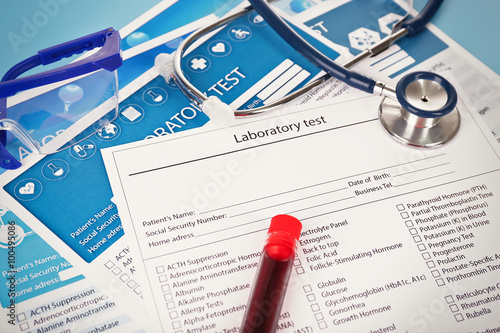 Blood in test tubes, stethoscope, glasses and investigation form on the table, close-up