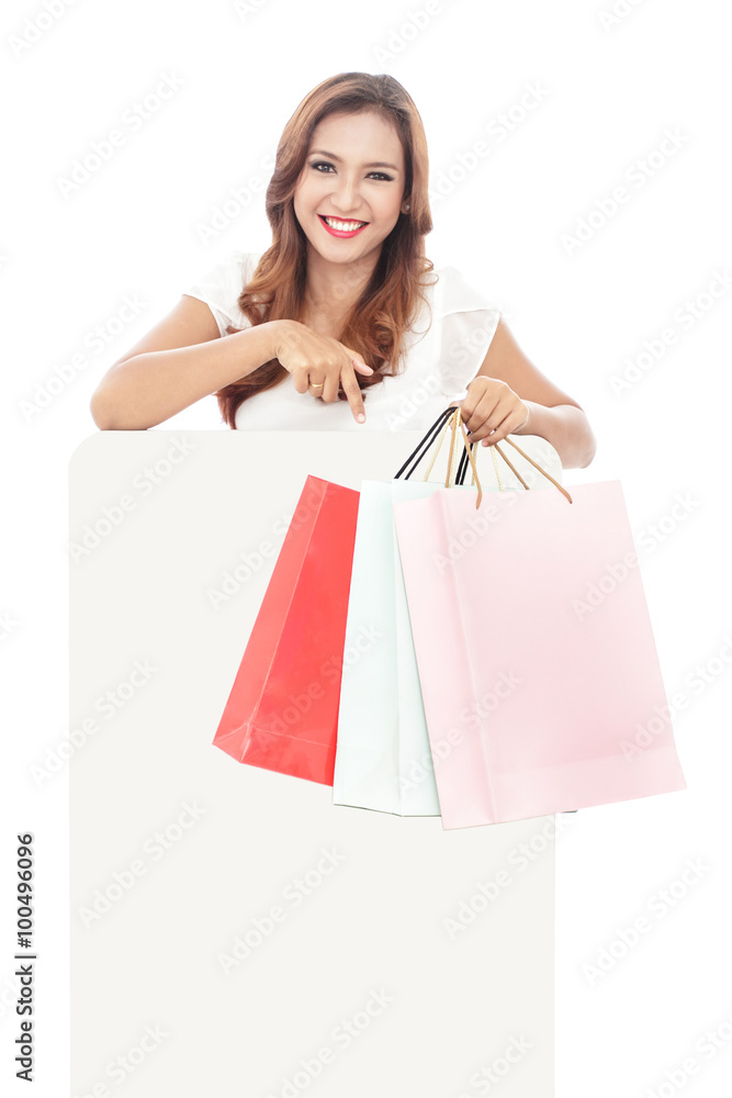 atrractive woman carrying shopping bags while pointing at blank