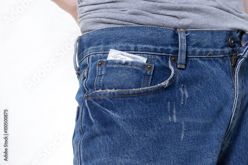 Condom in the pocket of blue jeans on isolated white background