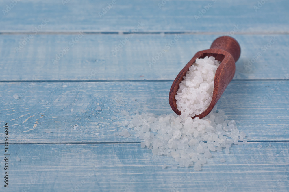 Obraz premium Sea salt in scoop on a wooden table