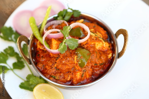 Butter chicken mutton curry or Indian style cottage cheese curry in a brass bowl with Salads.