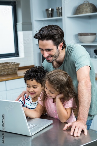 Smiling father using laptop with his children