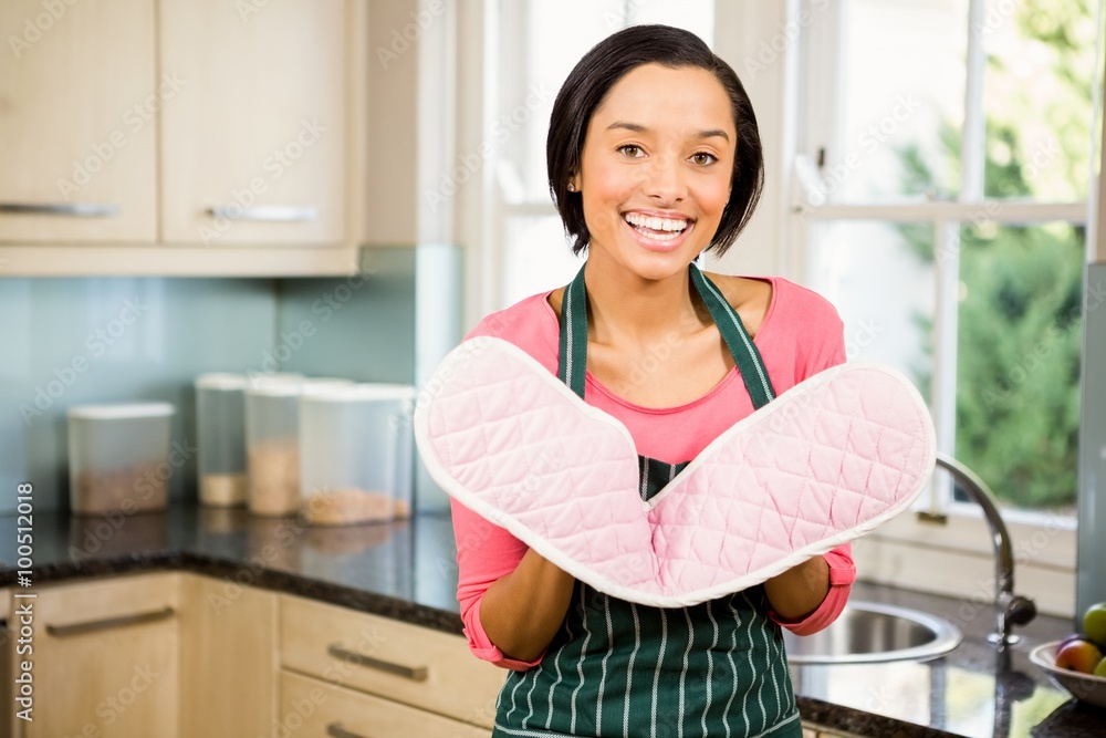 Smiling brunette showing pink oven mitt Smiling brunette showing pink oven mitt