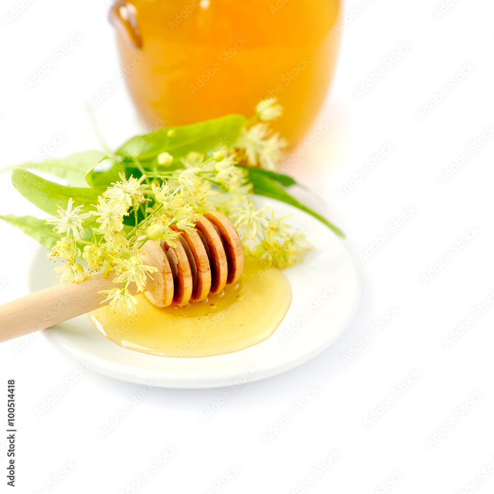 Honey dipper with honey with flowers of linden on white saucer Honey dipper with honey with flowers of linden on white saucer