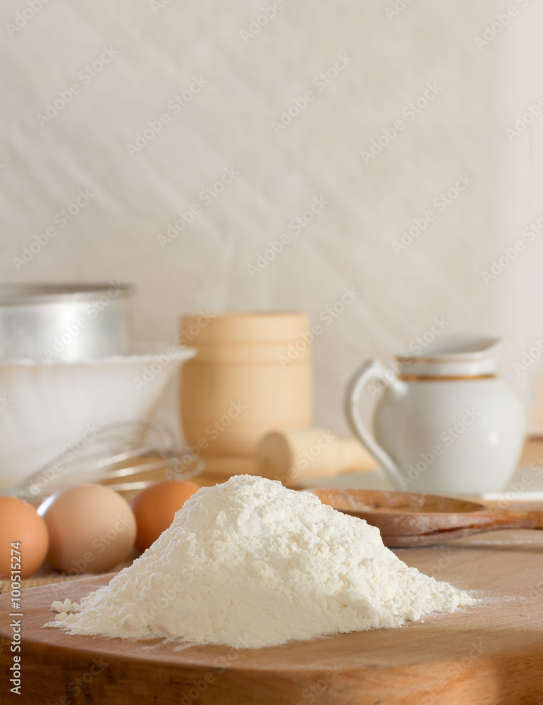 white wheat flour and raw chicken eggs to prepare the dough and kitchen utensils against a white wall. Concept of rustic kitchen, selective focus. Copy space. Free space for text white wheat flour and raw chicken eggs to prepare the dough and kitchen utensils against a white wall. Concept of rustic kitchen, selective focus. Copy space. Free space for text