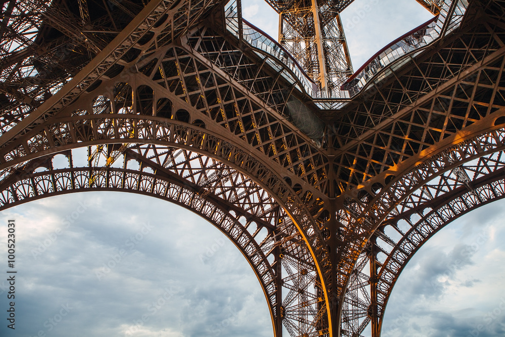 Fototapeta premium Close-up elements part of Eiffel tower in Paris against dramatic twilight sky at evening summer time.