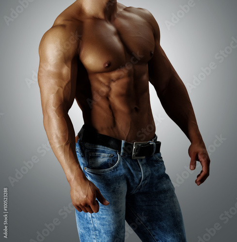 Красивый торс мускулистого мужчины в голубых джинсах.