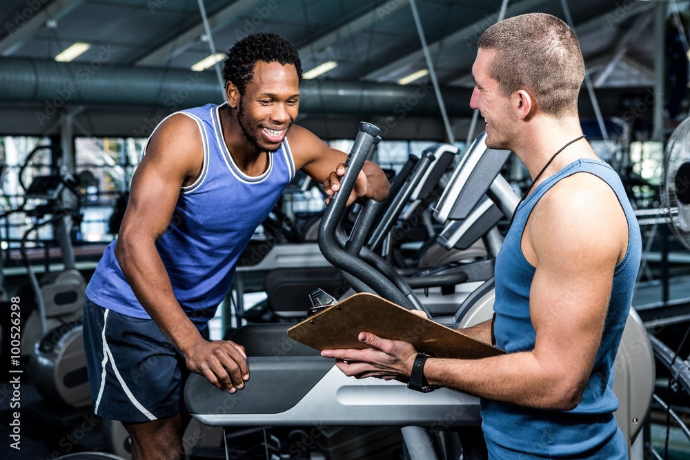 Muscular man discussing performance with trainer Muscular man discussing performance with trainer
