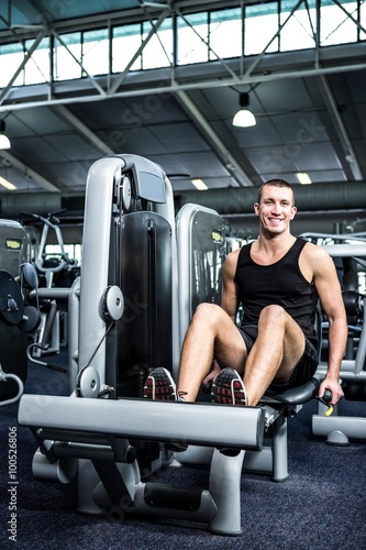 Muscular man using exercise machine for legs