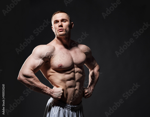 Strong muscular man posing in studio over dark background