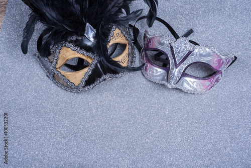two carnival masks with feathers on glitter