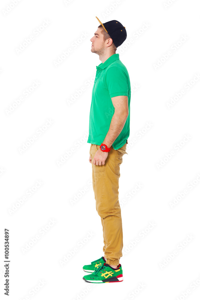 Fullbody profile portrait of young man standing in studio isolat