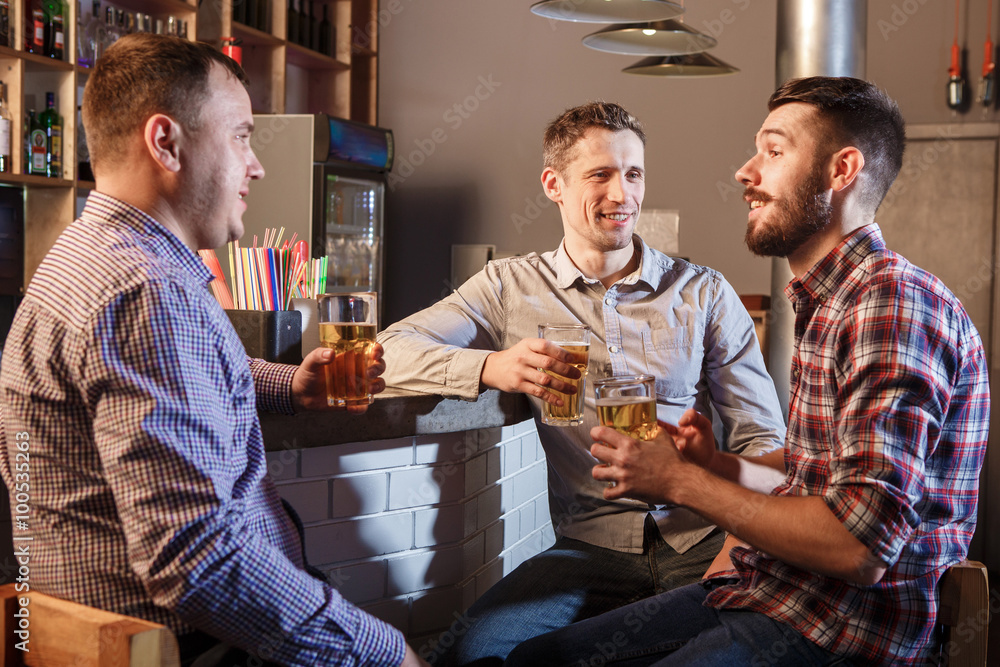 Happy friends drinking beer at counter in pub Happy friends drinking beer at counter in pub