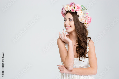 Attractive cheerful young woman in white dress and flower wreath
