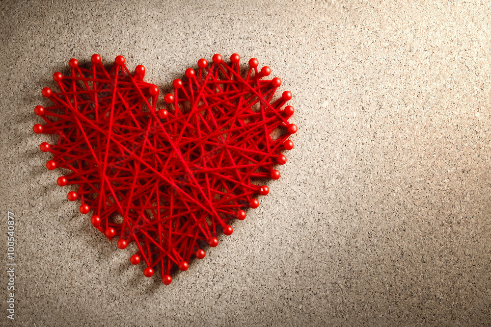 Red heart made from wool pinned into corkboard Red heart made from wool pinned into corkboard