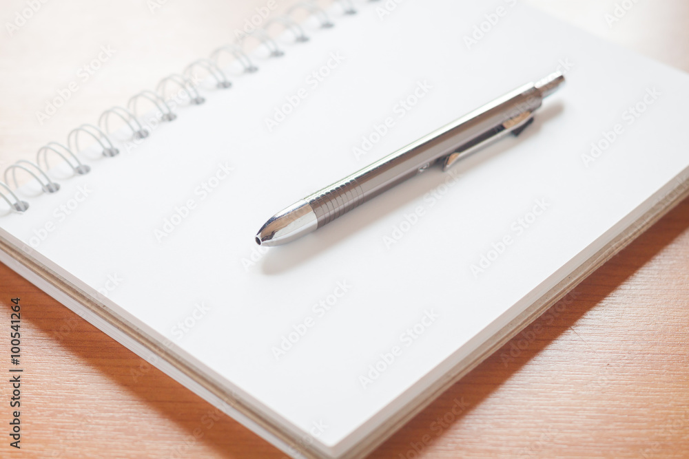 Pen on open blank white notebook on the desk Pen on open blank white notebook on the desk
