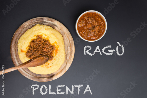 A dish of Polenta with bolognese soup (aka Ragu) standing on a black-board. Ragu and polenta on the blackboard