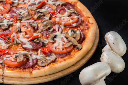 closeup Tasty pizza with tomatoes, mushroom, sausage, basil and