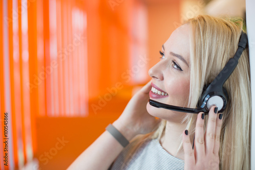 Portrait of support phone operator in headset at workplace. To p