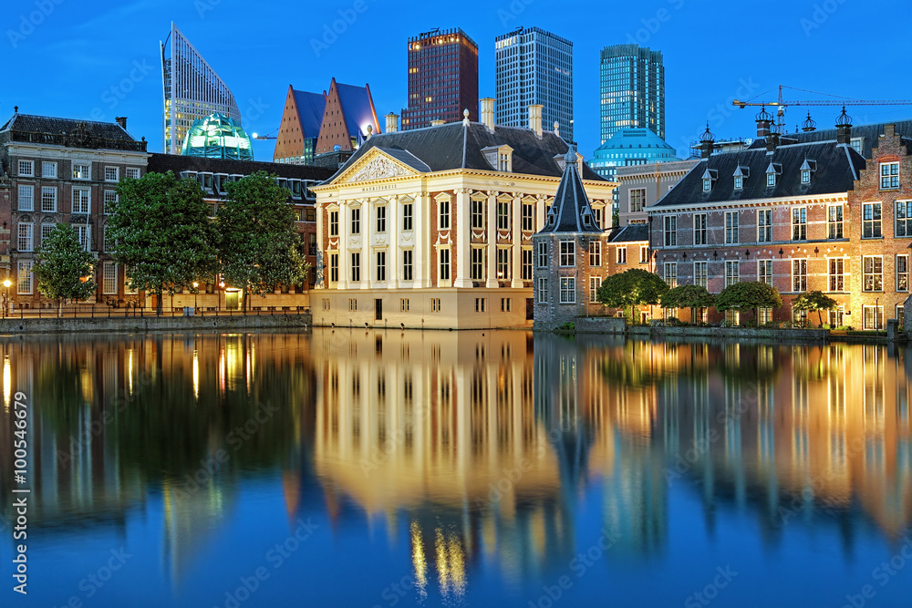 The Hague, Netherlands. The Mauritshuis on the shore of Hofvijver Pond (Court Pond) on the background of the city's skyscrapers in the evening.